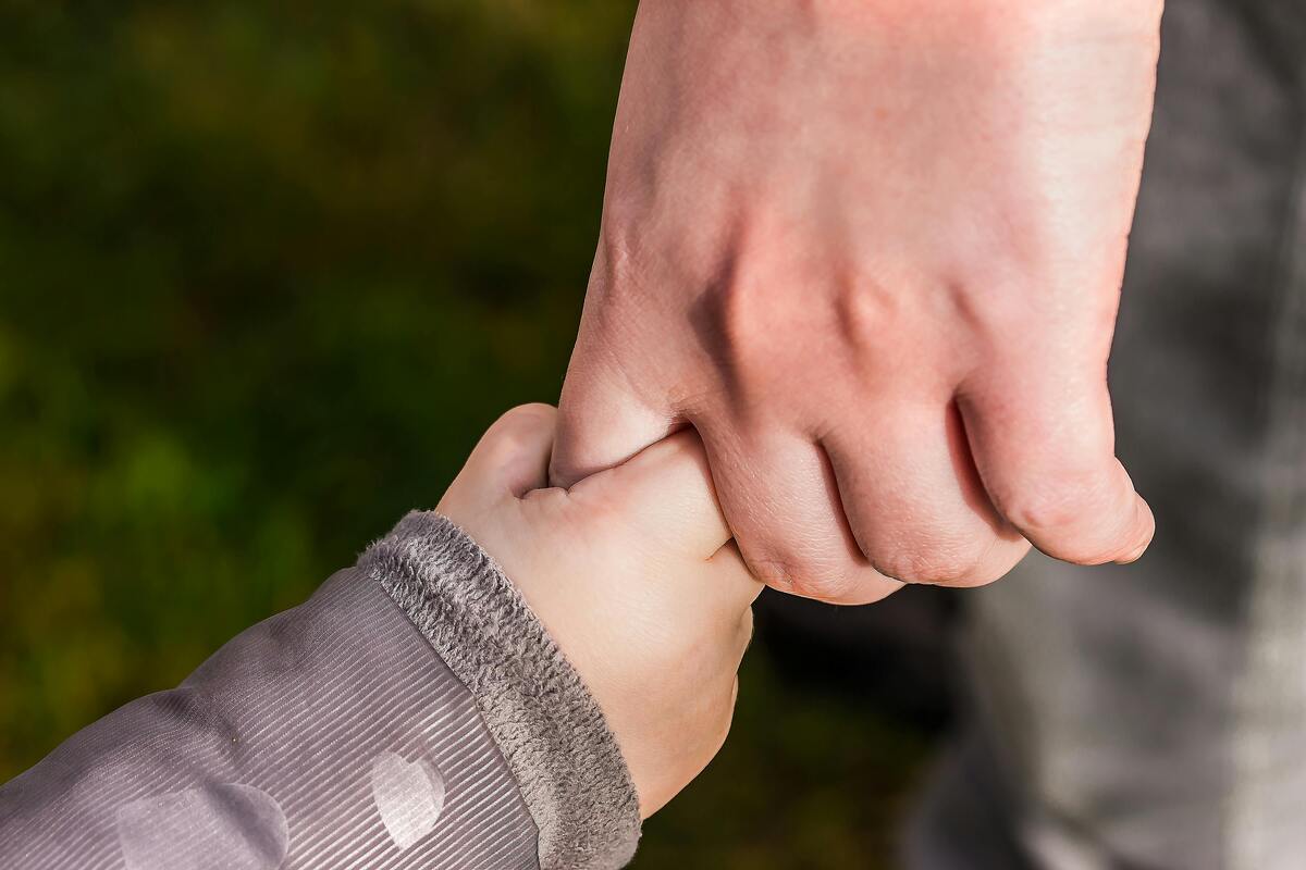 Adult holding a child’s hand representing Enlaze Communications’ support services for family law firms handling client communication, scheduling, and case support.