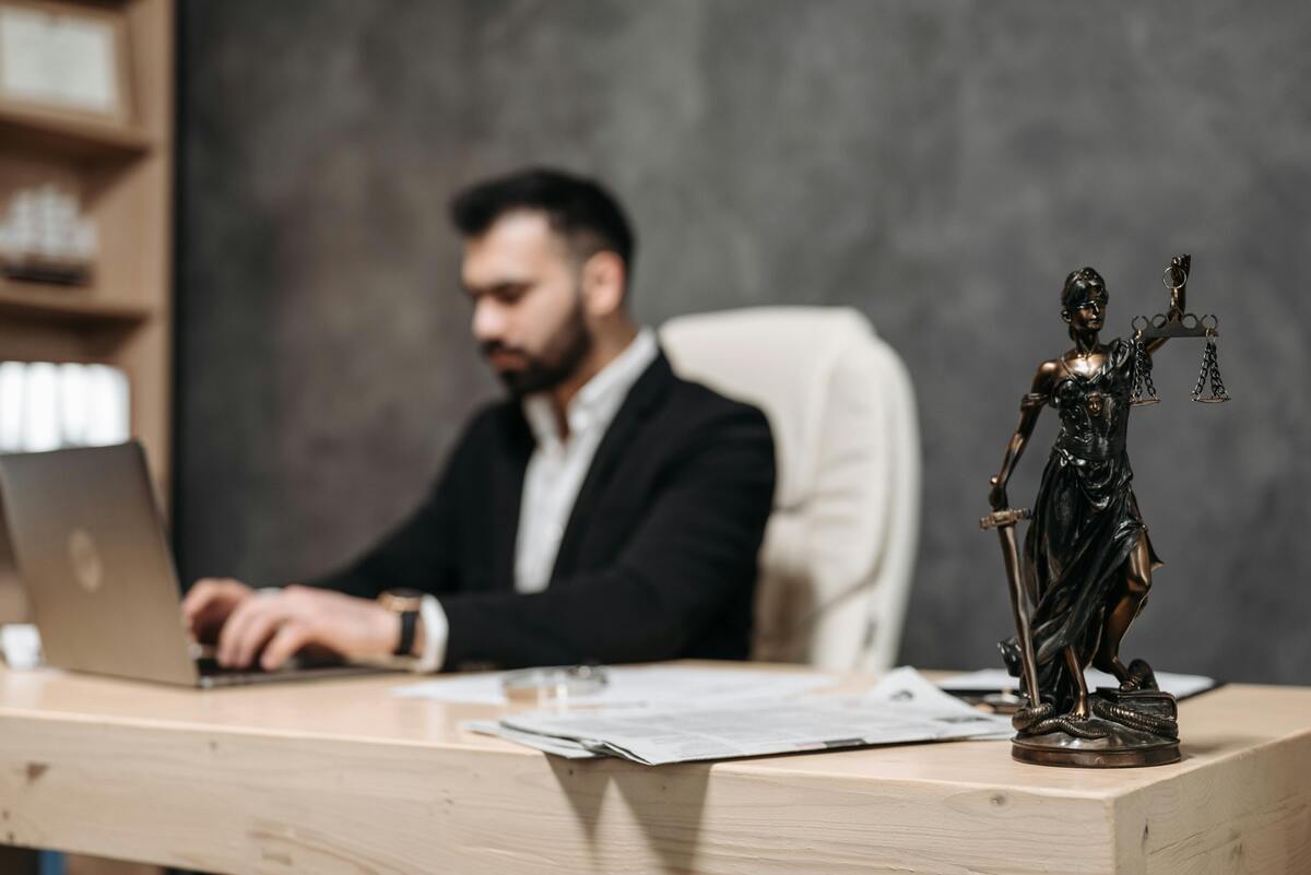 Attorney working at a desk with legal documents and scales of justice representing Enlaze Communications’ support services for solo and small law firms.