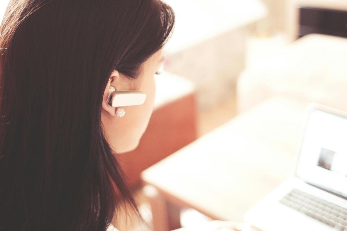 Woman using a headset while working on a laptop, representing Enlaze Communications’ virtual legal assistant support for responsive communication and remote law firm support.