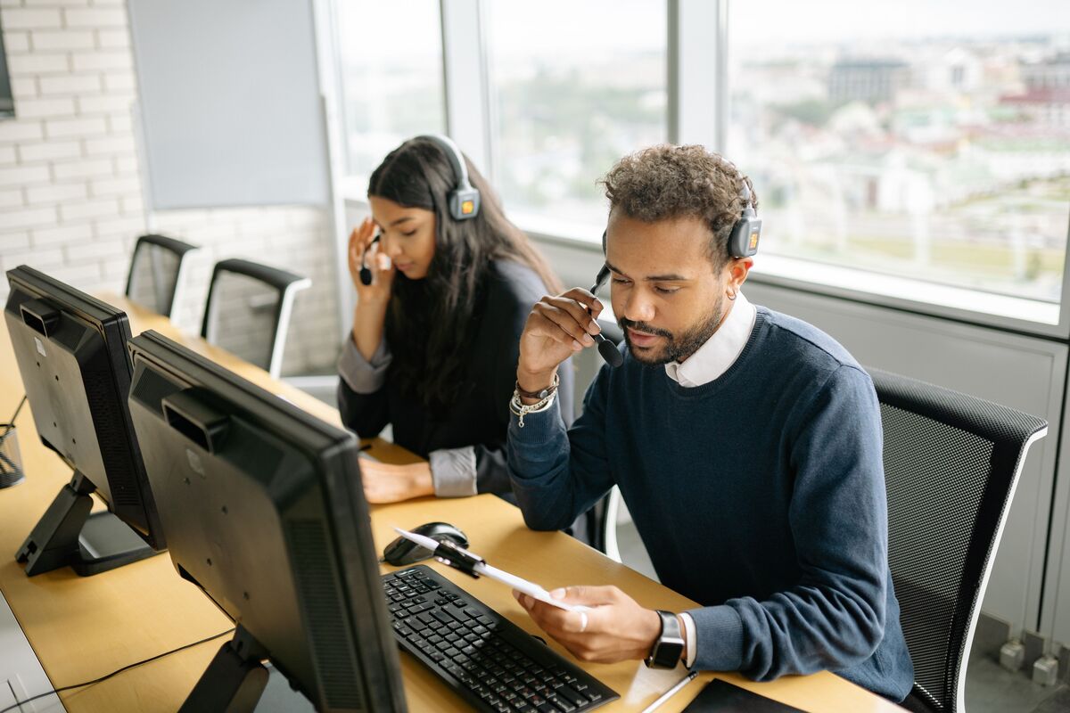 Two support professionals wearing headsets at computers, representing virtual legal assistant support for firm leaders looking for a cost-effective staffing solution