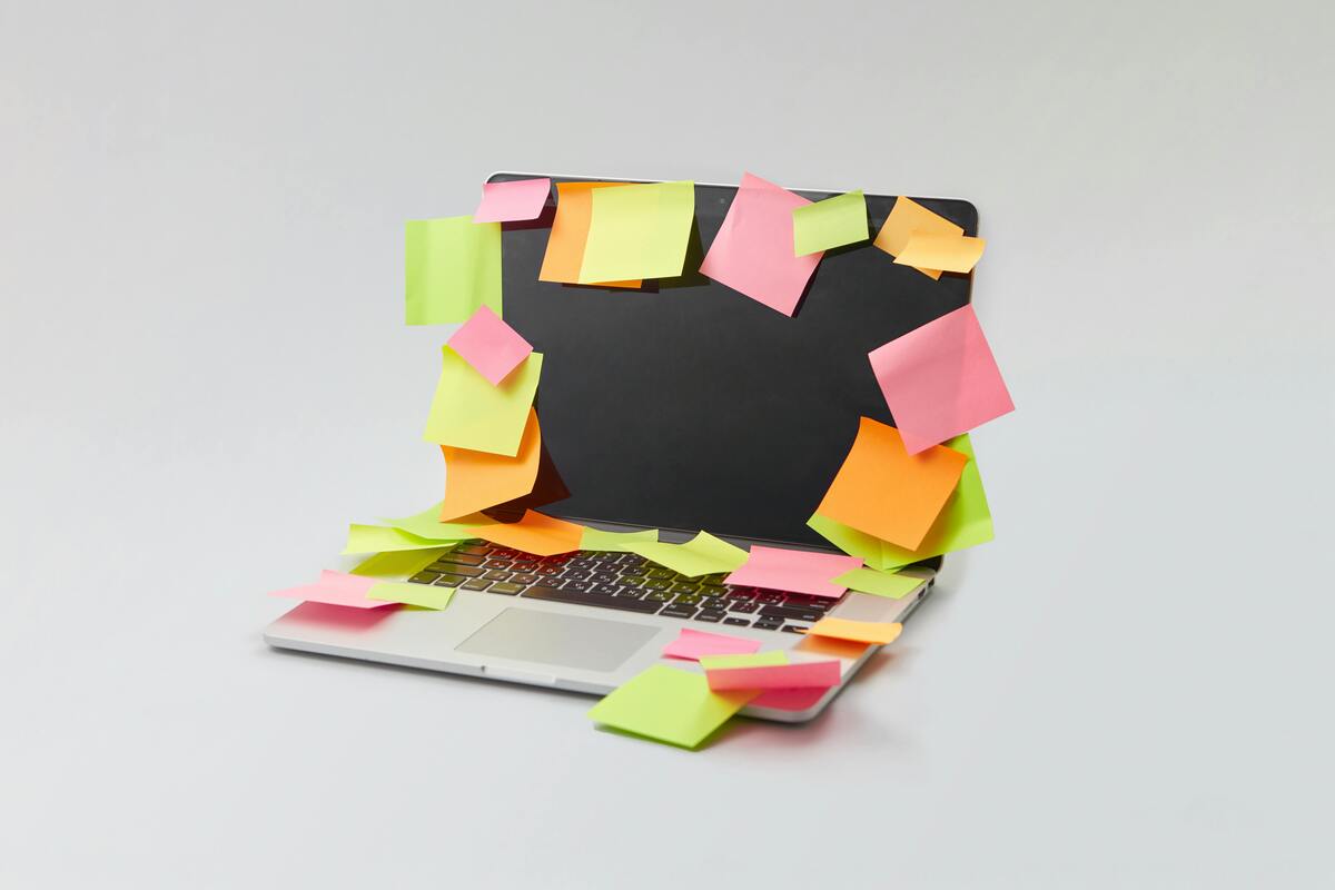Laptop covered with sticky notes representing heavy document requests and communication workloads for immigration law firms that may need virtual legal assistant support